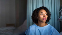 A female patient sits on a hospital bed.