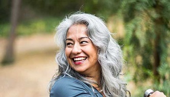 A smiling middle-aged woman exercises outside.