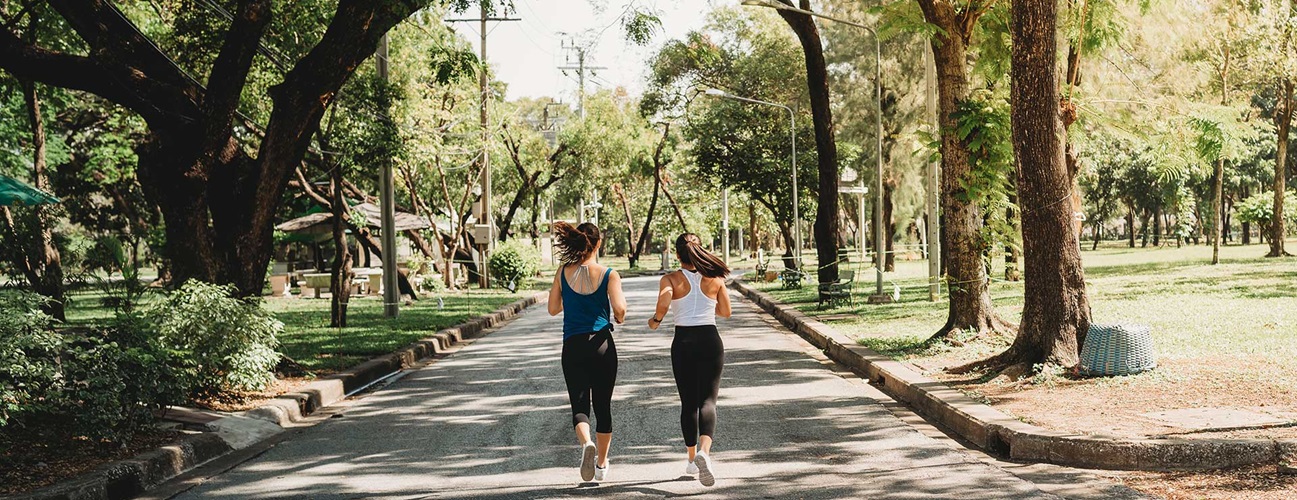 Two women jog together through a park.