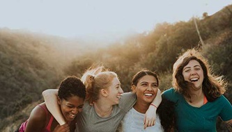 A group of female friends smile outside.